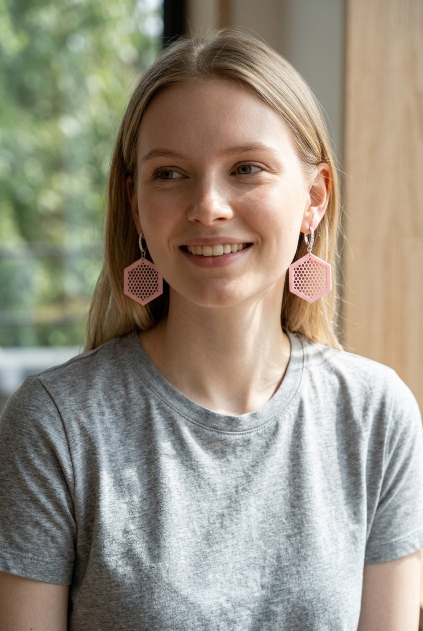 RISITEC - Timeless By Design Ohrringe mit rosa Wabenmuster-Anhängern und feinsilberplattierten Creolen an einer Frau