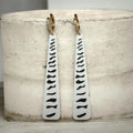 RISITEC - Timeless By Design long drop earrings with white and black abstract patterns, and crystal-encrusted gold hoops.